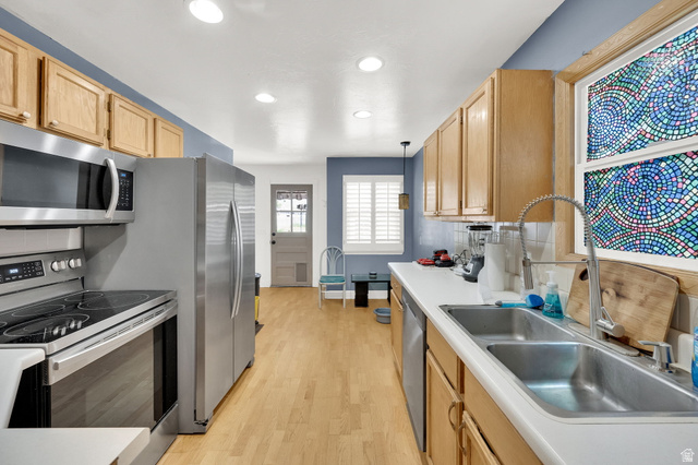 4635 Box Elder Street Murray, UT 84107 - Photo 8 of 21 Kitchen with stainless steel appliances, decorative backsplash, hanging light fixtures, light countertops, and light wood finished floors