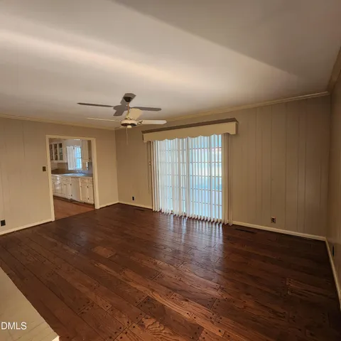 an empty room with wooden floor chandelier and windows