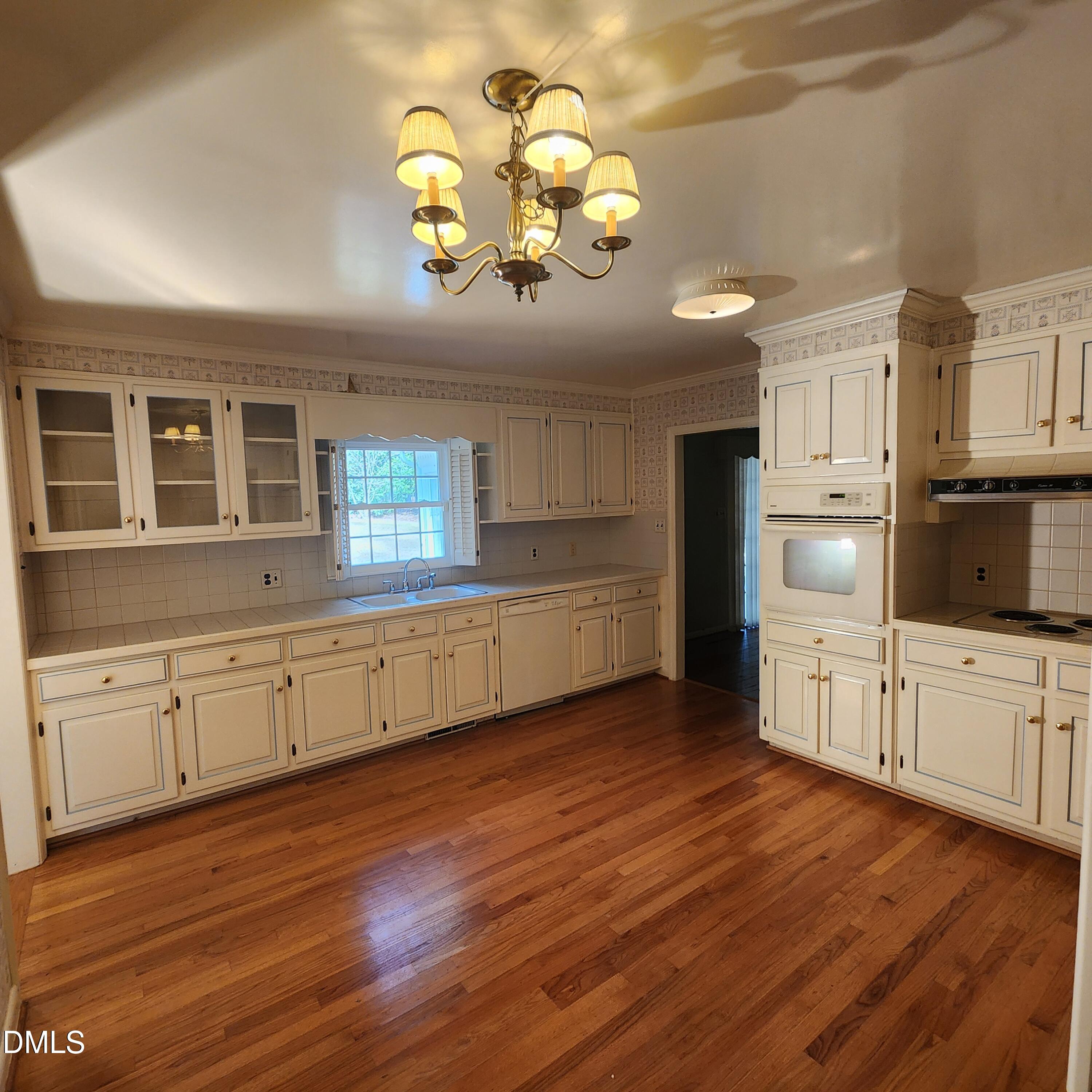 744 Durham Road Wake Forest, NC 27587 - Photo 4 of 25 a kitchen with stainless steel appliances granite countertop a stove a sink dishwasher and white cabinets with wooden floor