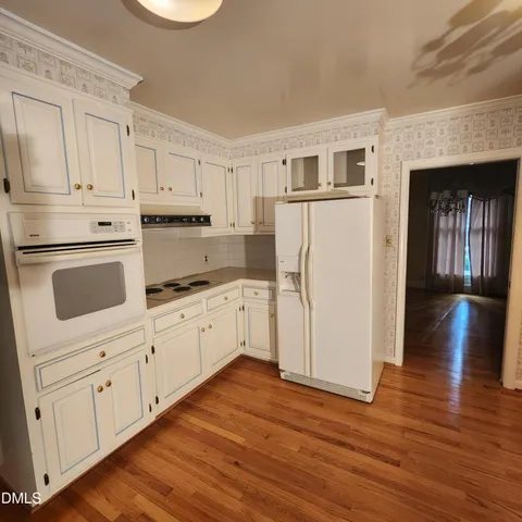 a kitchen with granite countertop white cabinets and white appliances