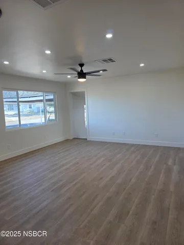 an empty room with windows and ceiling fan