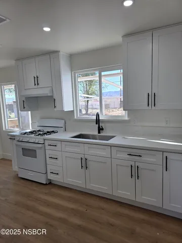a kitchen with granite countertop white cabinets sink and appliances