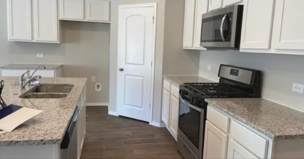 a kitchen with granite countertop a sink stove and cabinets