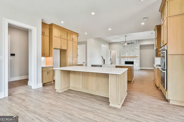 a large kitchen with a center island wooden floor and stainless steel appliances