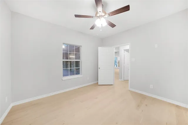 an empty room with chandelier fan and windows