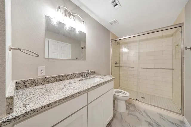 a bathroom with a granite countertop sink toilet and shower