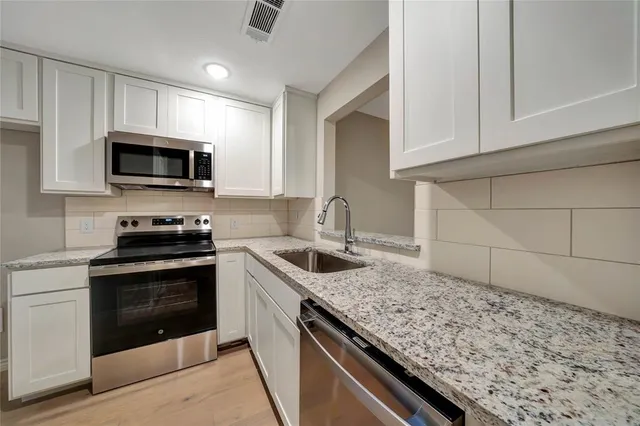 a kitchen with granite countertop a sink stove and microwave