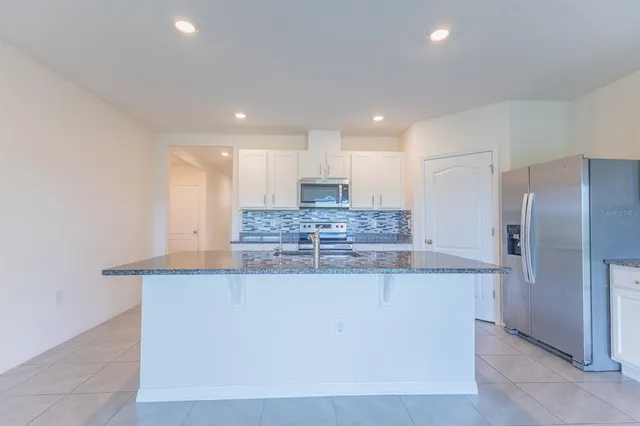 a large kitchen with stainless steel appliances kitchen island a large counter top and a refrigerator