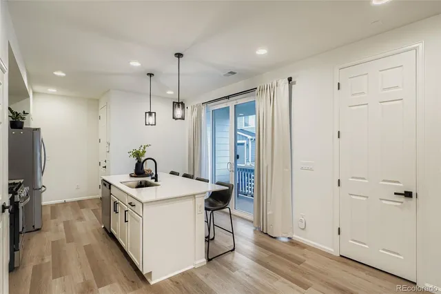 a white kitchen with a sink a counter space and stainless steel appliances