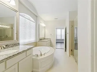 a bathroom with a granite countertop tub sink and mirror