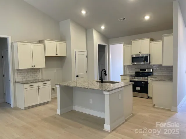 a kitchen with granite countertop white cabinets and stainless steel appliances