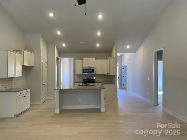 a view of kitchen with kitchen island stainless steel appliances refrigerator stove microwave and cabinets