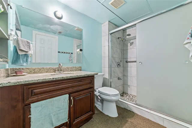 a bathroom with a granite countertop sink toilet and shower