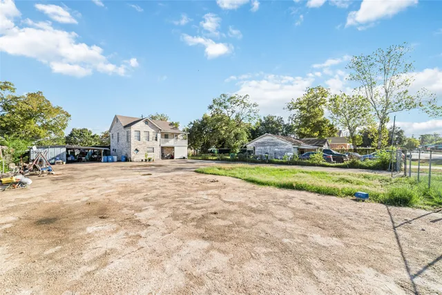 a view of white house with a big yard and potted plants