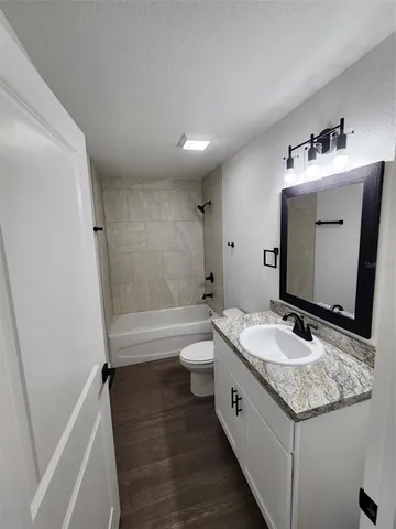 an empty room with wooden floor chandelier fan and windows