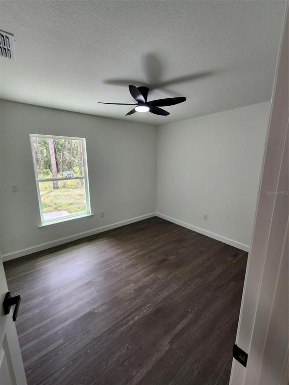 24370 Falcon Avenue Dunnellon, FL 34431 - Photo 9 of 24 an empty room with wooden floor chandelier fan and windows