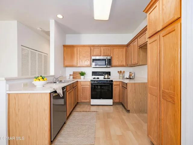 a kitchen with stainless steel appliances granite countertop a refrigerator a sink dishwasher a stove with wooden cabinets and a window