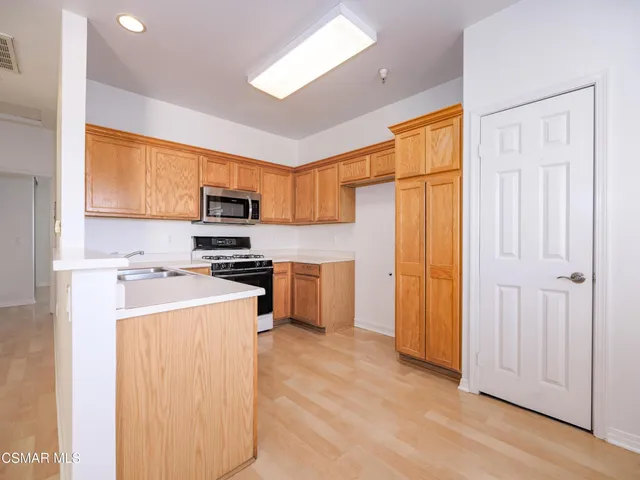 a kitchen with a refrigerator a stove top oven a sink and dishwasher with wooden floor