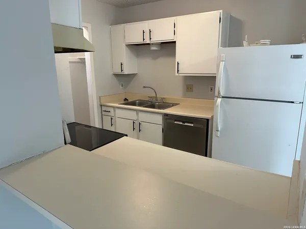 a kitchen with stainless steel appliances a refrigerator a sink and white cabinets