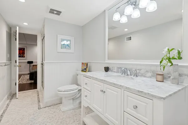 a bathroom with a granite countertop sink a toilet and a mirror