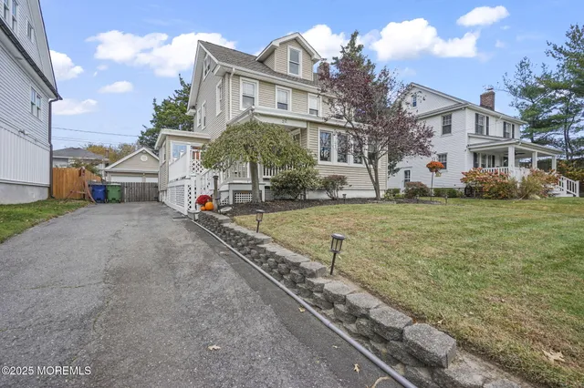 a view of a white house with a yard and lawn chairs