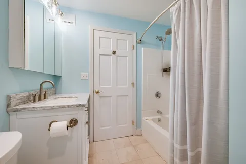 a bathroom with a granite countertop sink a mirror a bathtub and shower