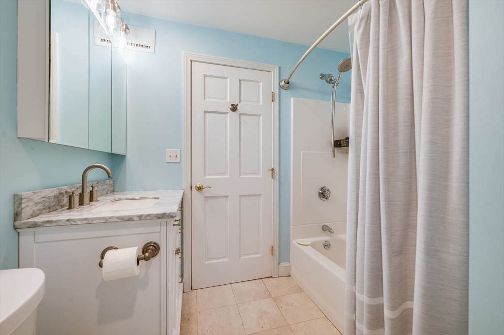 39 Chestnut Street, Unit 2C Stoneham, MA 02180 - Photo 15 of 21 a bathroom with a granite countertop sink a mirror a bathtub and shower