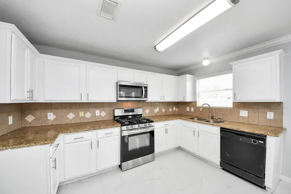 a kitchen with granite countertop white cabinets sink and stainless steel appliances