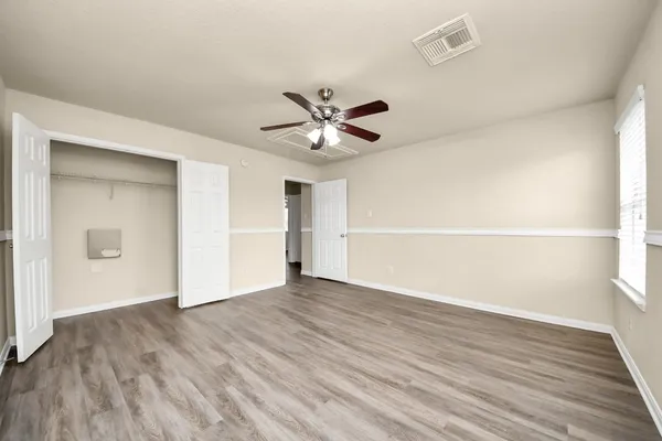 an empty room with wooden floor and a ceiling fan
