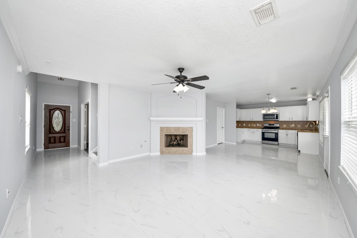 2406 Gwenfair Drive Spring, TX 77373 - Photo 8 of 44 an empty room with fireplace and a kitchen view