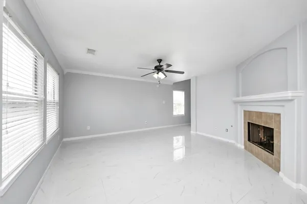 a view of an empty room with chandelier fan and fire place