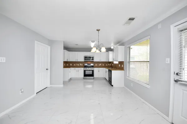 a kitchen with granite countertop white cabinets sink and stainless steel appliances