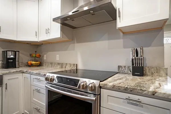 a kitchen with granite countertop white cabinets and white appliances