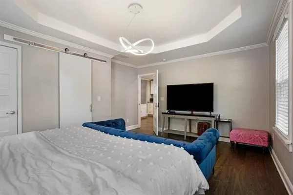 a bedroom with bed and a flat tv screen on dresser