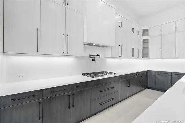 a large white kitchen with stainless steel appliances kitchen island granite countertop a sink and cabinets