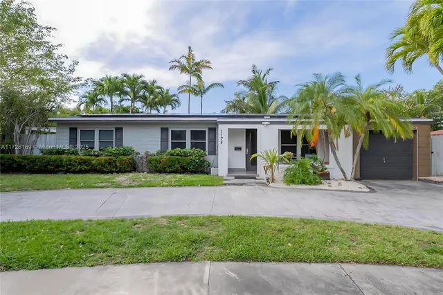 a front view of a house with a yard and potted plants