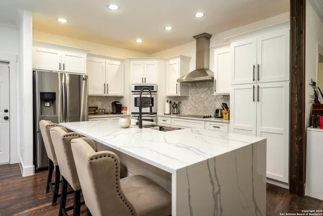 a large kitchen with kitchen island a stove a sink a refrigerator and cabinets