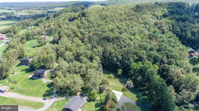 an aerial view of residential house with outdoor space and trees all around