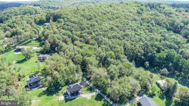 an aerial view of residential house with outdoor space and trees all around