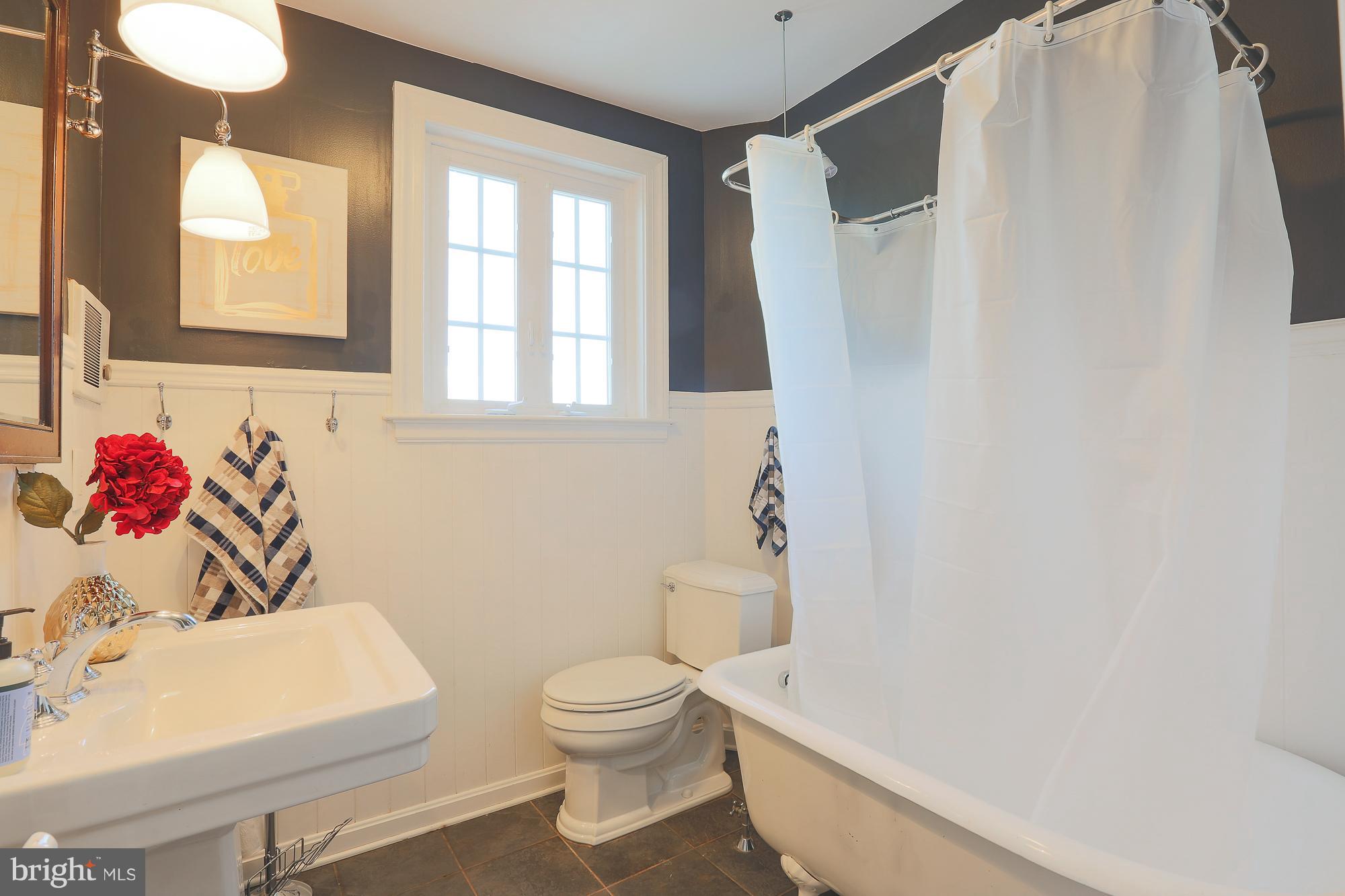 3628 Rexmere Road Baltimore, MD 21218 - Photo 20 of 28 a bathroom with a white toilet sitting next to a white sink and a shower curtain