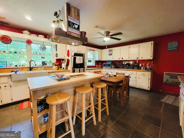 a kitchen with stainless steel appliances kitchen island granite countertop a table chairs sink and cabinets
