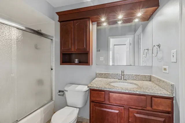 a bathroom with a granite countertop sink toilet and shower