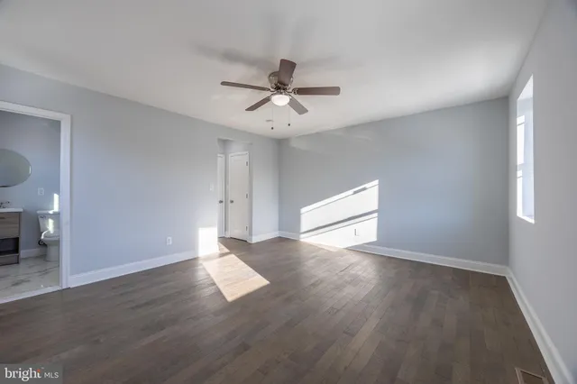 an empty room with wooden floor and ceiling fan
