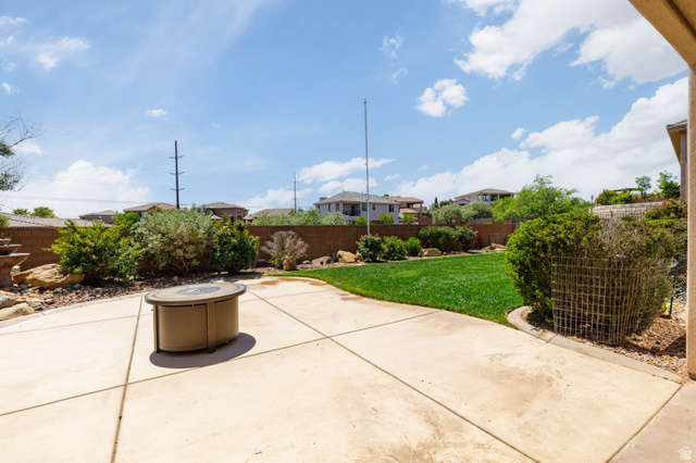 2005 West 450 S Circle St. George, UT 84770 - Photo 37 of 57 Expansive backyard featuring a concrete patio, a central fire pit, and a manicured lawn
