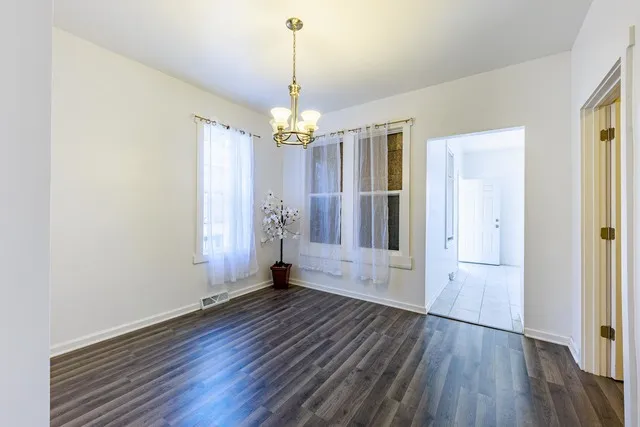 a view of a livingroom with wooden floor a ceiling fan and windows
