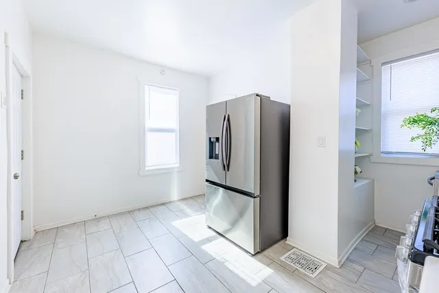a view of a refrigerator in kitchen and an empty room