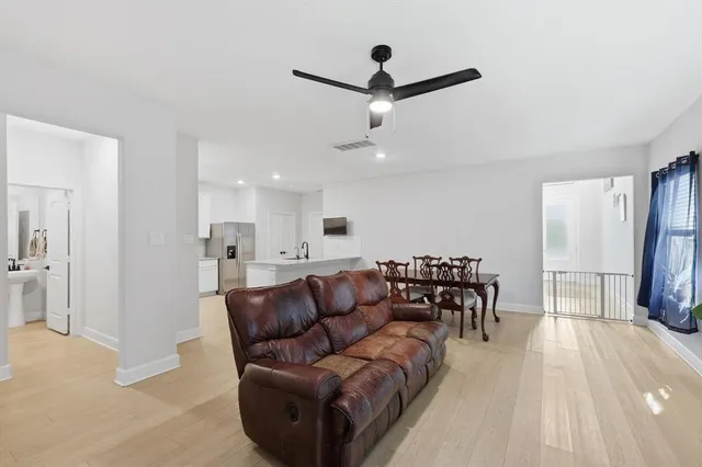 a living room with furniture and a dining table with wooden floor