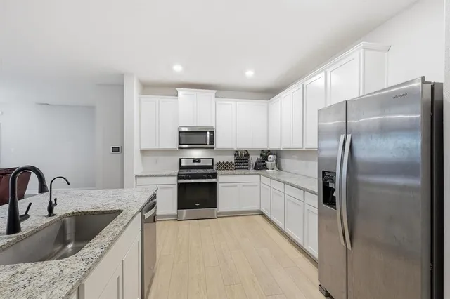 a kitchen with kitchen island granite countertop a sink stainless steel appliances and refrigerator
