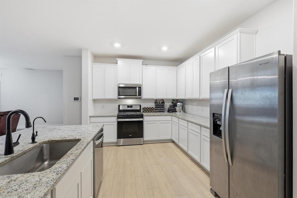 1334 Windemere Way Princeton, TX 75407 - Photo 3 of 31 a kitchen with kitchen island granite countertop a sink stainless steel appliances and refrigerator
