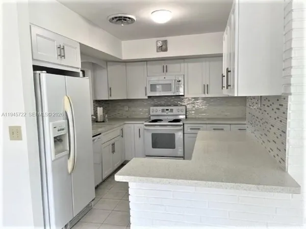 a kitchen with white cabinets and white appliances